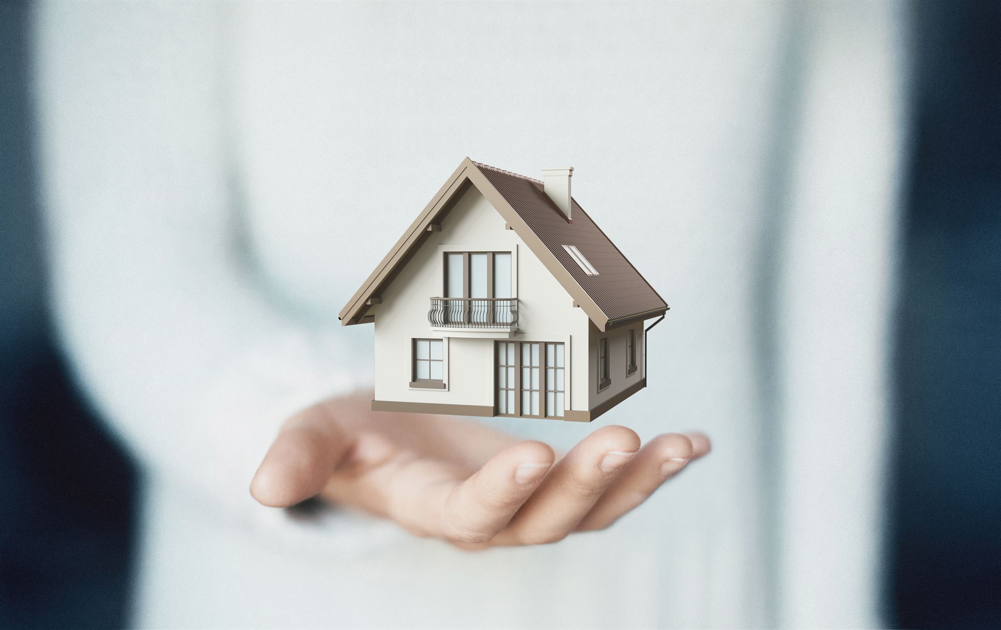 Hands holding umbrella protecting house model